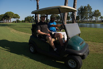 Image showing golf players driving cart at course