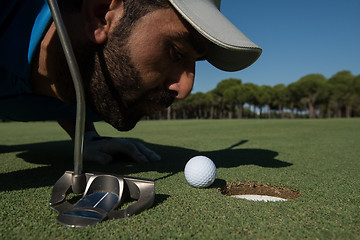 Image showing golf player blowing ball in hole