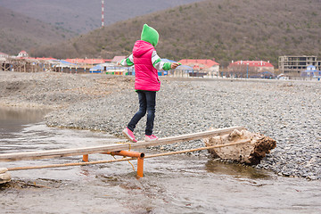 Image showing The little girl nearly went to the other side of the stream on the board