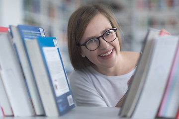 Image showing portrait of famale student selecting book to read in library