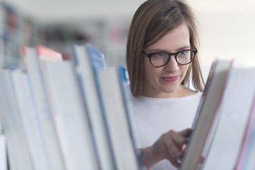 Image showing portrait of famale student selecting book to read in library