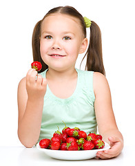 Image showing Little girl is eating strawberries