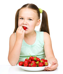 Image showing Little girl is eating strawberries