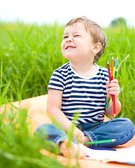 Image showing Little boy is playing with pencils