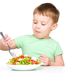 Image showing Cute little boy is eating vegetable salad