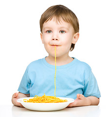 Image showing Little boy is eating spaghetti