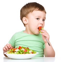 Image showing Cute little boy is eating vegetable salad