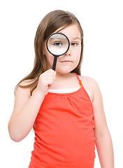 Image showing Cute little girl is looking through magnifier