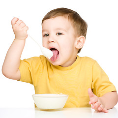 Image showing Cute little boy is eating cottage cheese