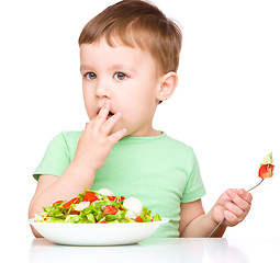 Image showing Cute little boy is eating vegetable salad