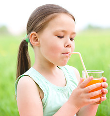 Image showing Little girl is drinking orange juice