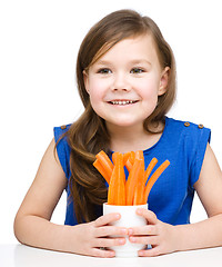 Image showing Cute little girl is eating carrot