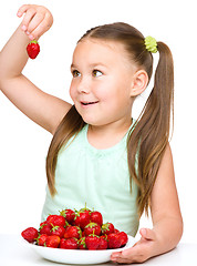 Image showing Cheerful little girl is eating strawberries