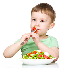 Image showing Cute little boy is eating vegetable salad