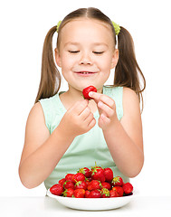 Image showing Little girl is eating strawberries