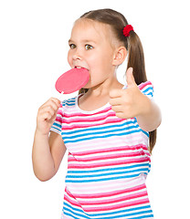 Image showing Little girl with lollipop showing thumb up gesture