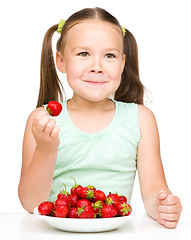 Image showing Cheerful little girl is eating strawberries