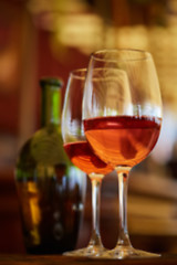 Image showing two glasses filled with red wine and bottle in background