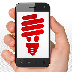 Image showing Business concept: Hand Holding Smartphone with Energy Saving Lamp on display