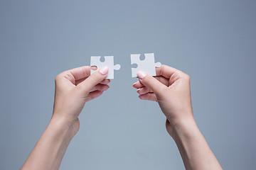 Image showing The puzzles in hands on gray 
