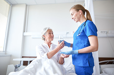 Image showing nurse giving medicine to senior woman at hospital