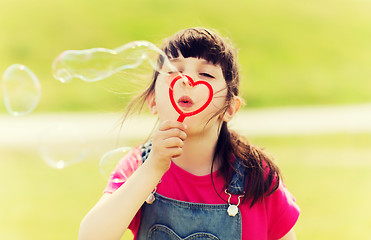 Image showing little girl blowing soap bubbles outdoors