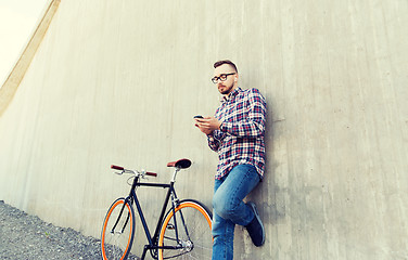 Image showing hipster man in earphones with smartphone and bike