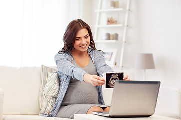 Image showing happy pregnant woman with ultrasound image at home