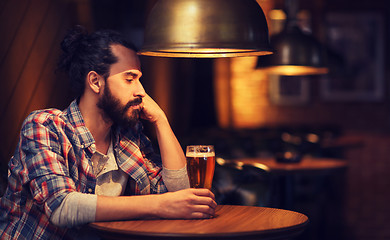 Image showing unhappy lonely man drinking beer at bar or pub