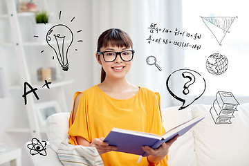 Image showing smiling young asian woman reading book at home