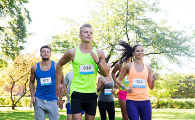 Image showing happy young sportsmen racing wit badge numbers