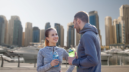 Image showing smiling couple with bottles of water in city