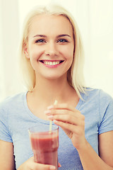 Image showing smiling woman drinking juice or shake at home