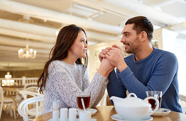 Image showing happy couple with tea holding hands at restaurant