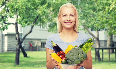 Image showing smiling young woman with vegetables in home garden