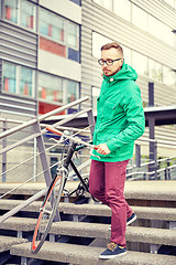 Image showing young hipster man carrying fixed gear bike in city