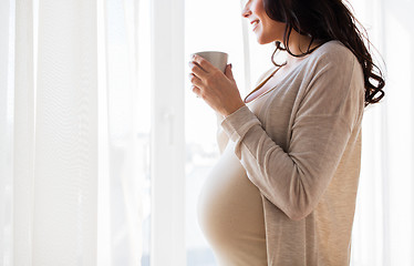 Image showing close up of pregnant woman with tea cup at window