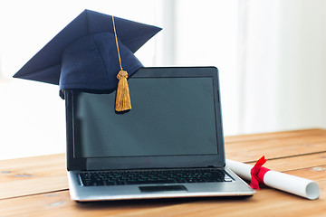 Image showing close up of laptop with mortarboard and diploma