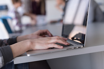 Image showing close up of business womans hand typing on laptop with team on m