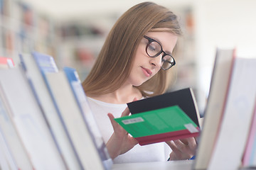 Image showing portrait of famale student selecting book to read in library