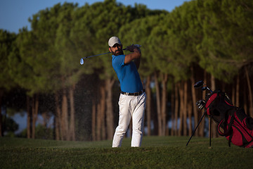 Image showing golfer hitting a sand bunker shot on sunset