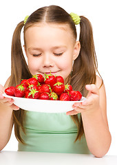 Image showing Cheerful little girl is smelling strawberries