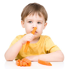 Image showing Little boy is eating carrot