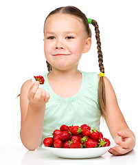 Image showing Happy little girl is eating strawberries