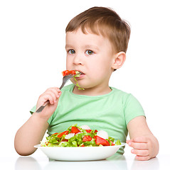 Image showing Cute little boy is eating vegetable salad