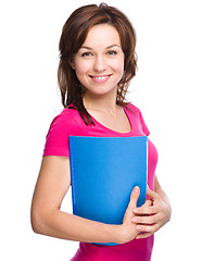 Image showing Young skinny student girl is holding exercise book