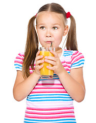 Image showing Little girl is drinking orange juice