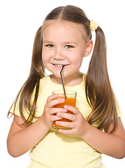 Image showing Little girl is drinking carrot juice