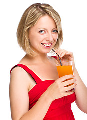 Image showing Young woman is drinking carrot juice