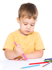 Image showing Little boy is drawing using color pencils